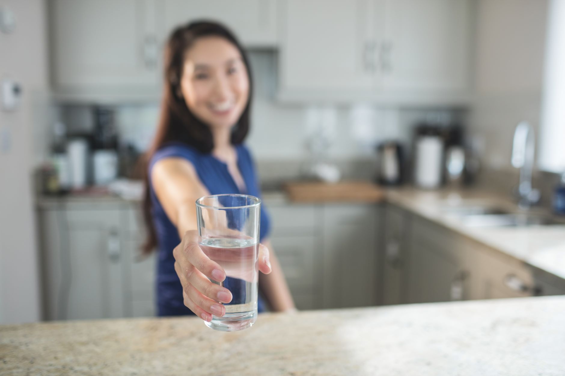 15180160-young-woman-holding-a-glass-of-water-in-kitchen2.jpg