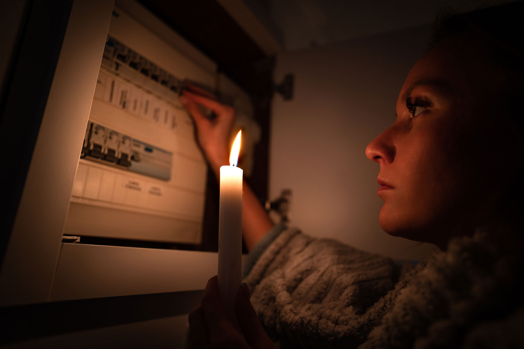 mp54338297-woman-checking-fuse-box-at-home-during-power-outage-or.jpg