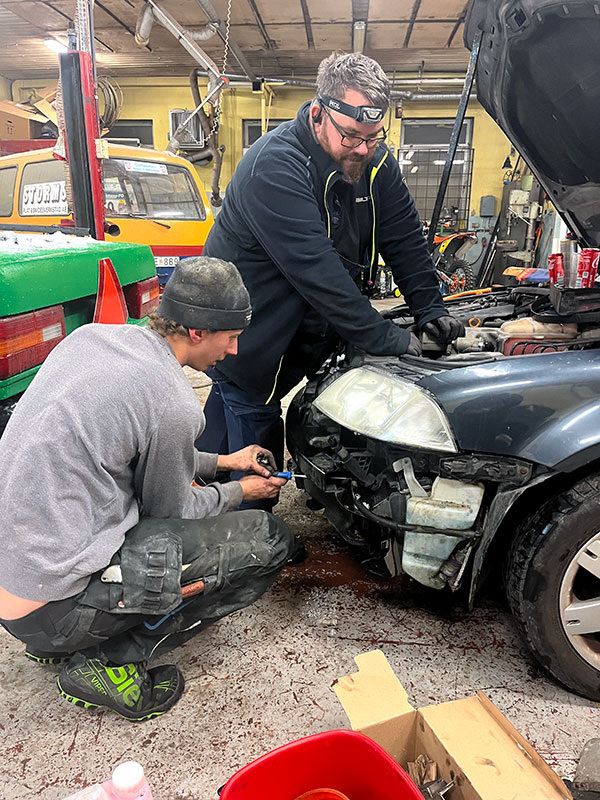 Två-män-meckar-med-en-bil-i-ett-garage